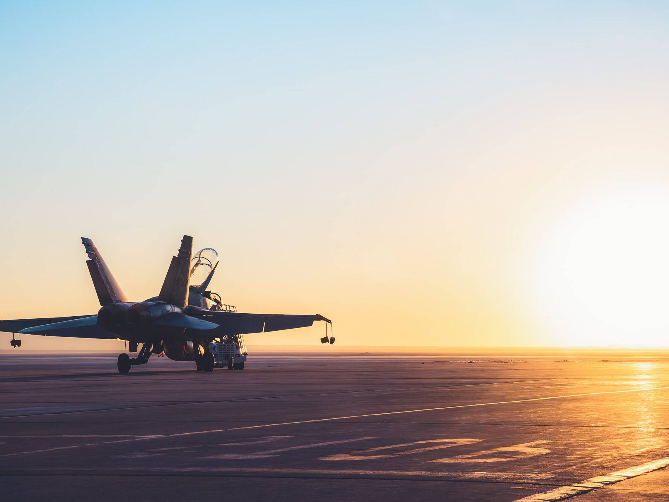 military jet on runway during sunset